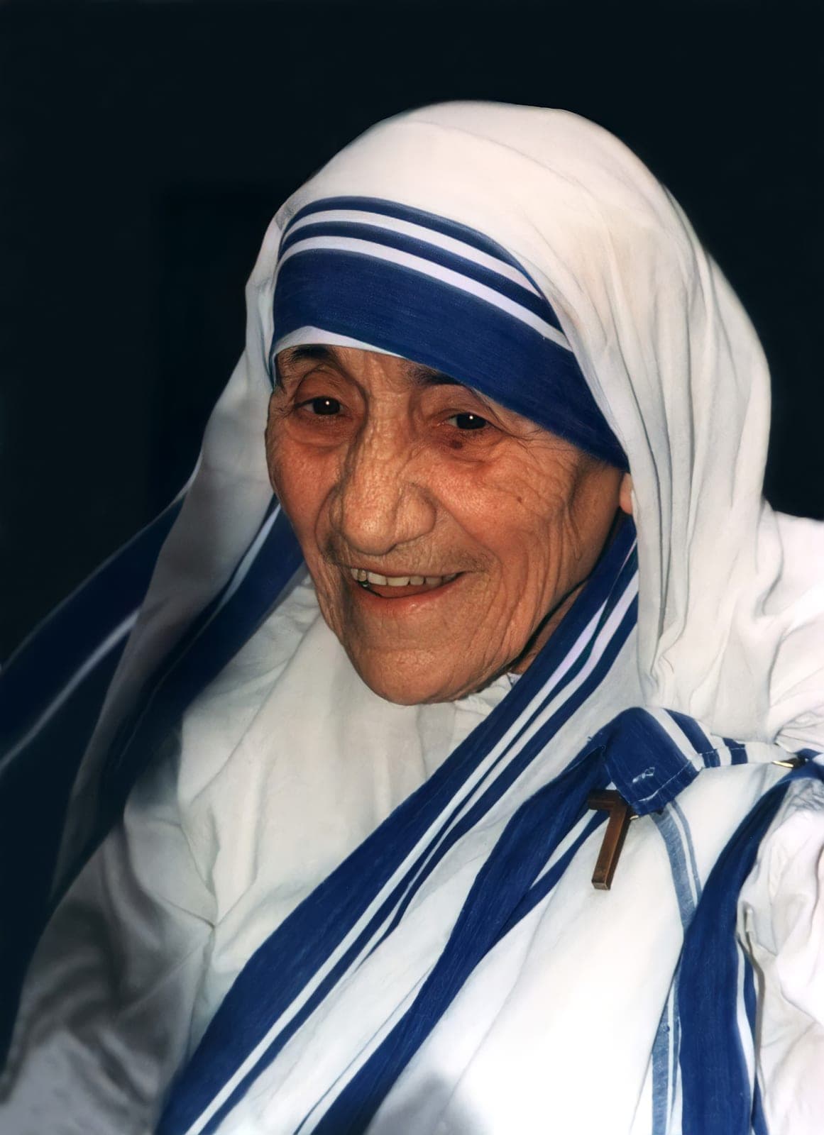 A photograph of Mother Teresa smiling, in the white sari with blue stripes of the Missionaries of Charity