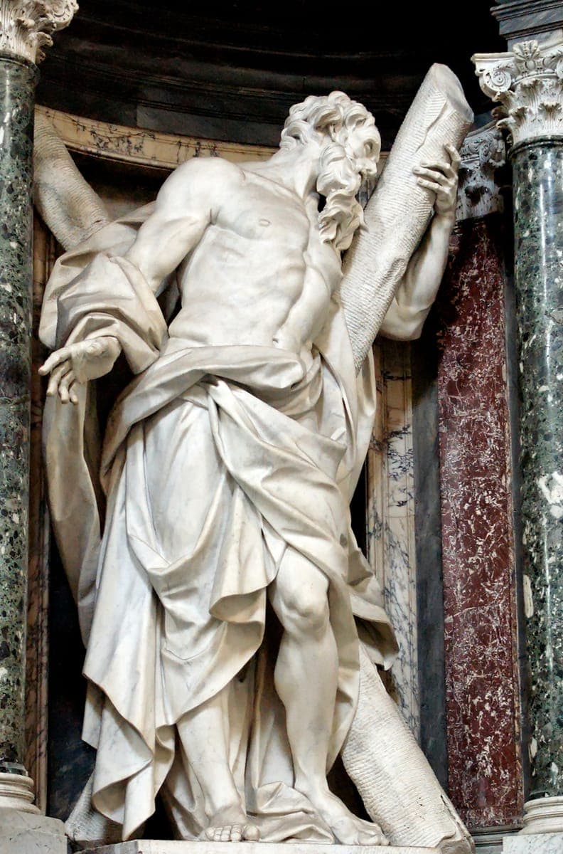 Camillo Rusconi's white marble statue of St. Andrew in a niche of coloured marble in the nave of the Archbasilica of St. John Lateran in Rome, the apostle leaning against a large X-shaped cross