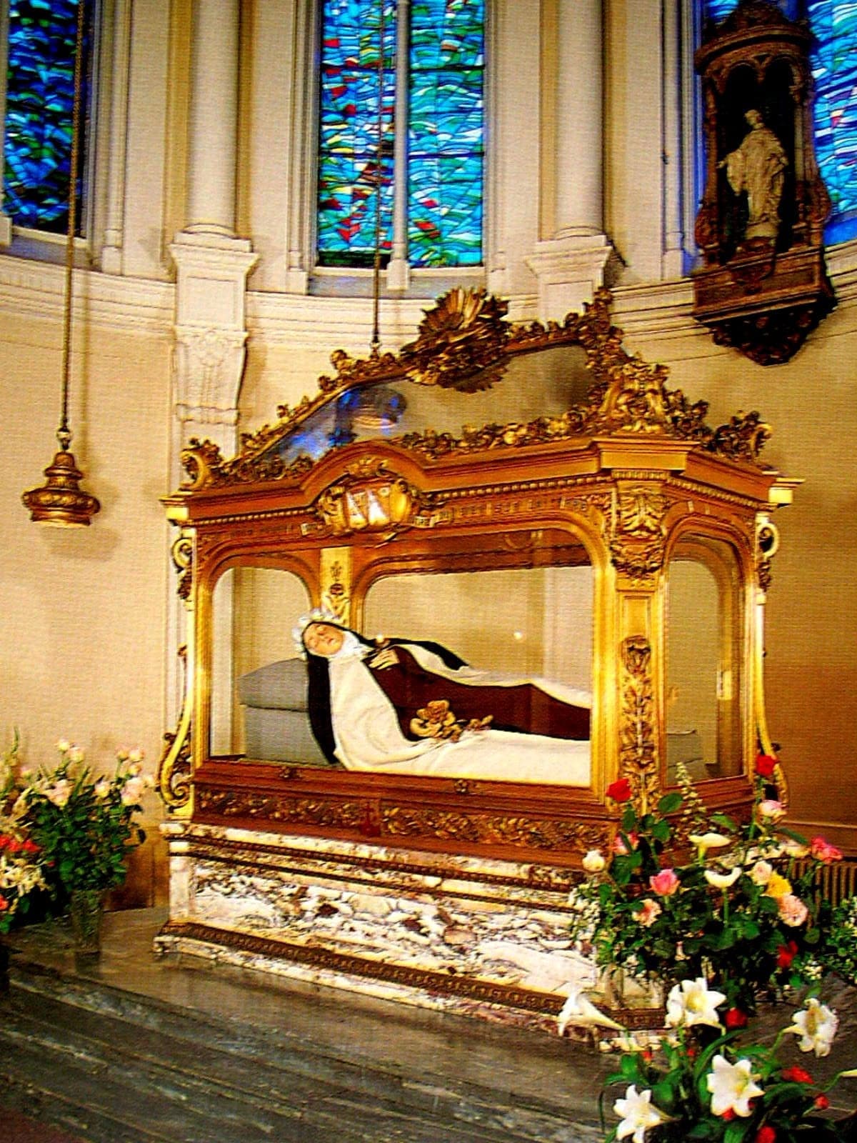 The gilded reliquary shrine of St. Thérèse at Lisieux, her recumbent effigy beneath a carved canopy