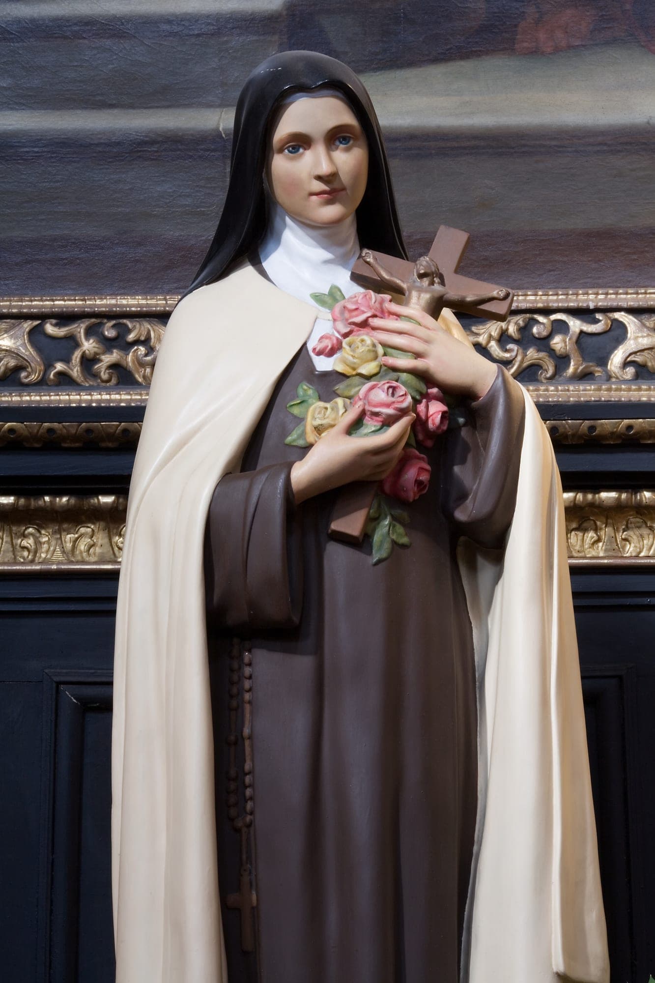 Statue of St. Thérèse of Lisieux in her Carmelite habit, holding a spray of roses and a crucifix